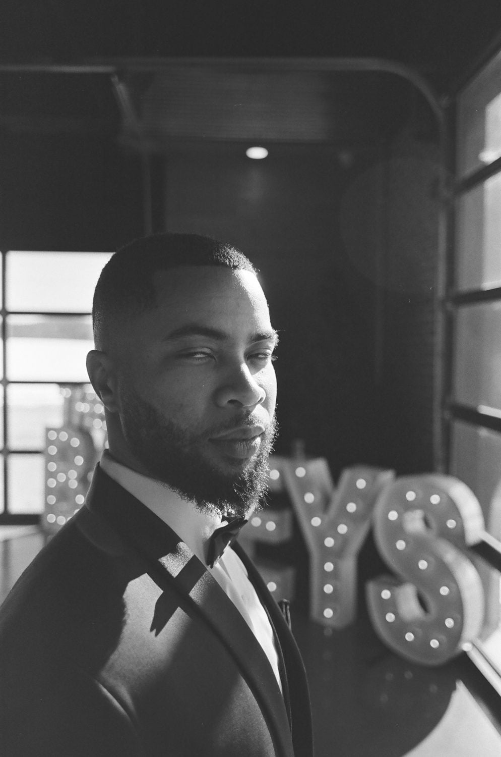 Black and white film portrait of the groom in a tuxedo