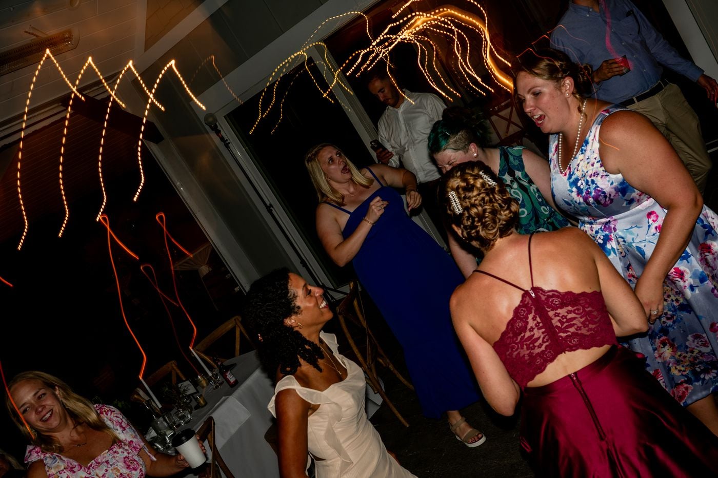 Guests dancing under string lights with light trails streaking across the reception floor