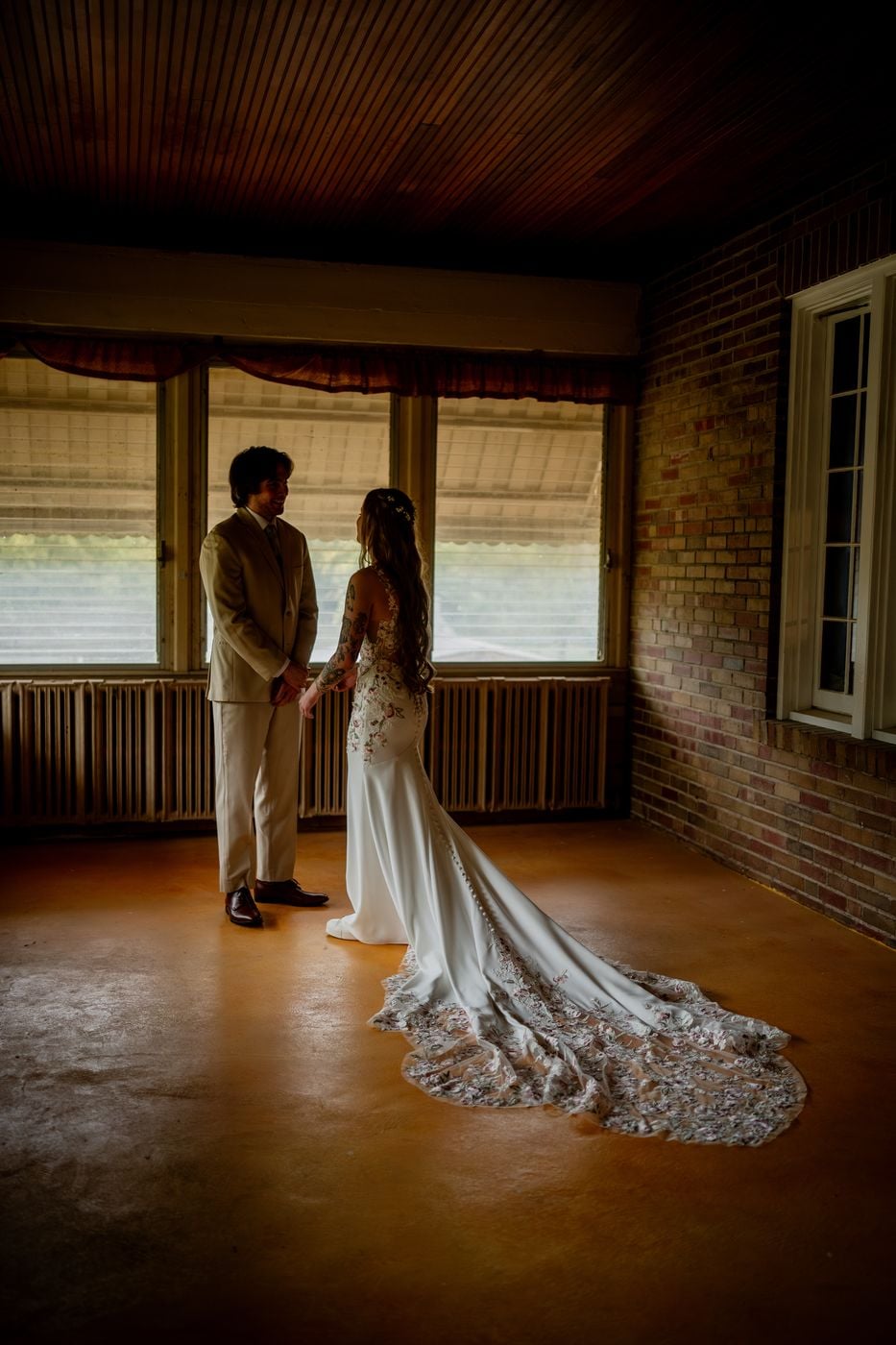Couple sharing their first look in a warm, golden-lit brick sunroom