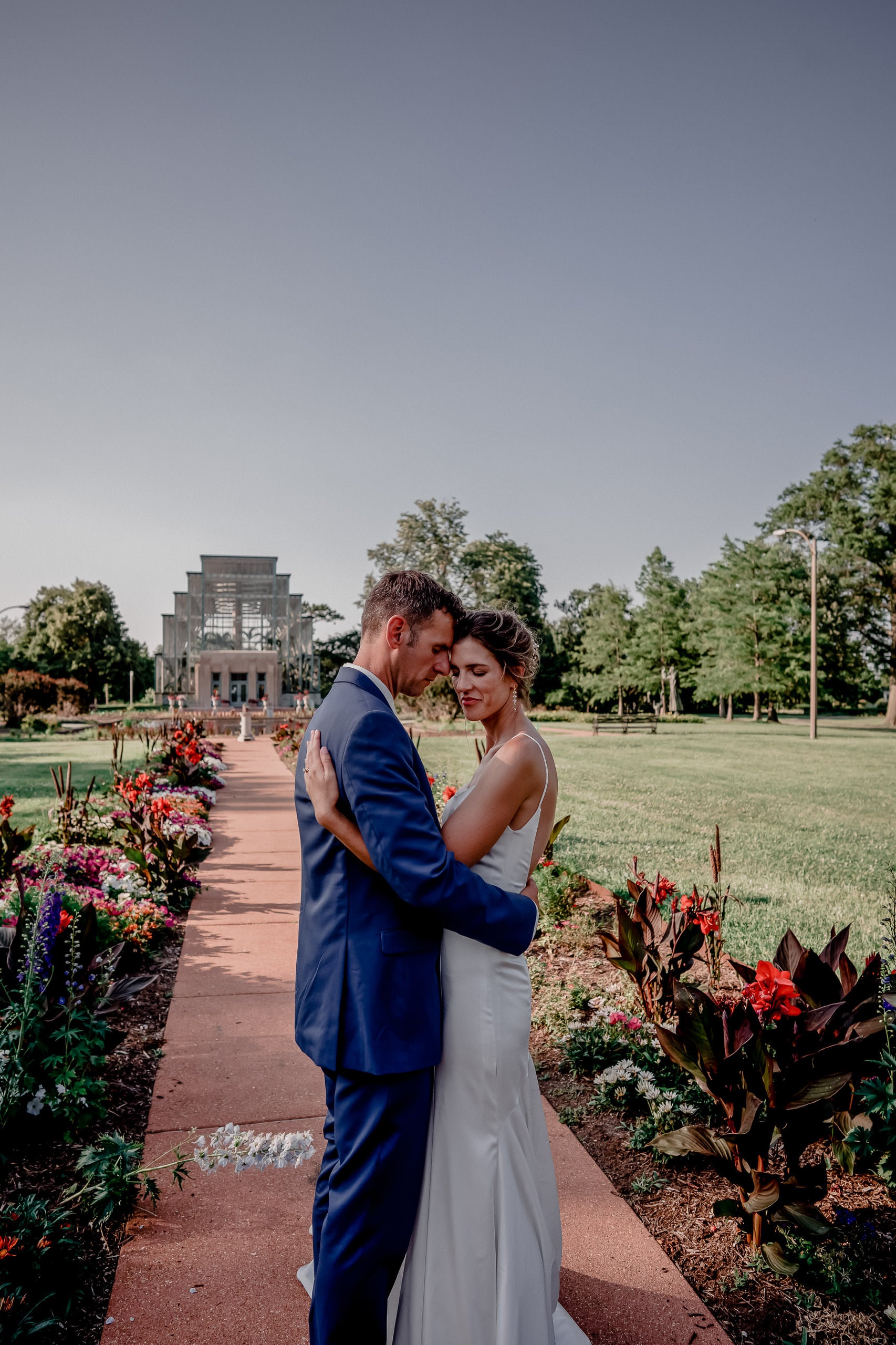 Bride and groom holding each other on a garden path at the Jewel Box in Forest Park, St. Louis