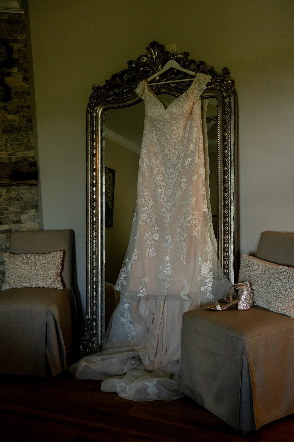 Wedding dress and shoes hanging on an ornate vintage mirror before the ceremony